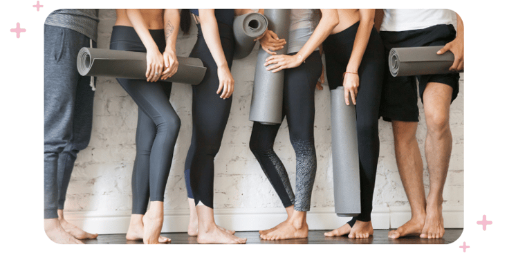 People holding foam mats before the yoga class begins