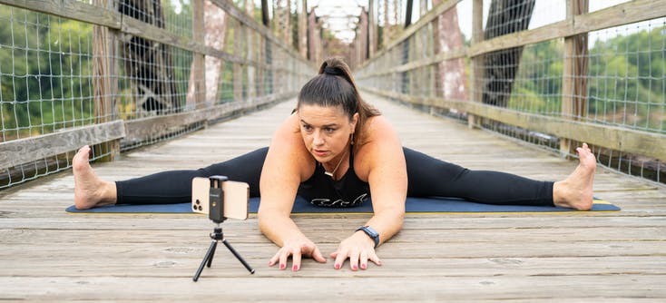 Kelly filming an online class on a footbridge