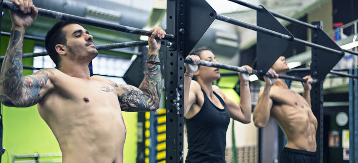 strength class in the gym doing pull-ups