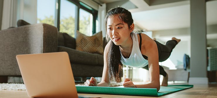 Online fitness class on floor with laptop and mat