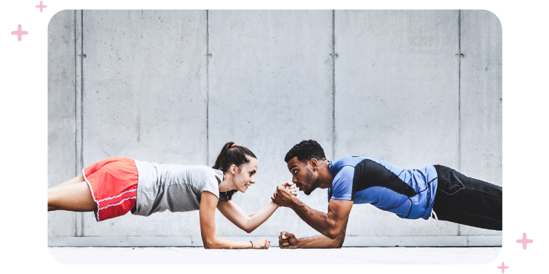 A fitness instructor high fives a fitness client while doing a plank