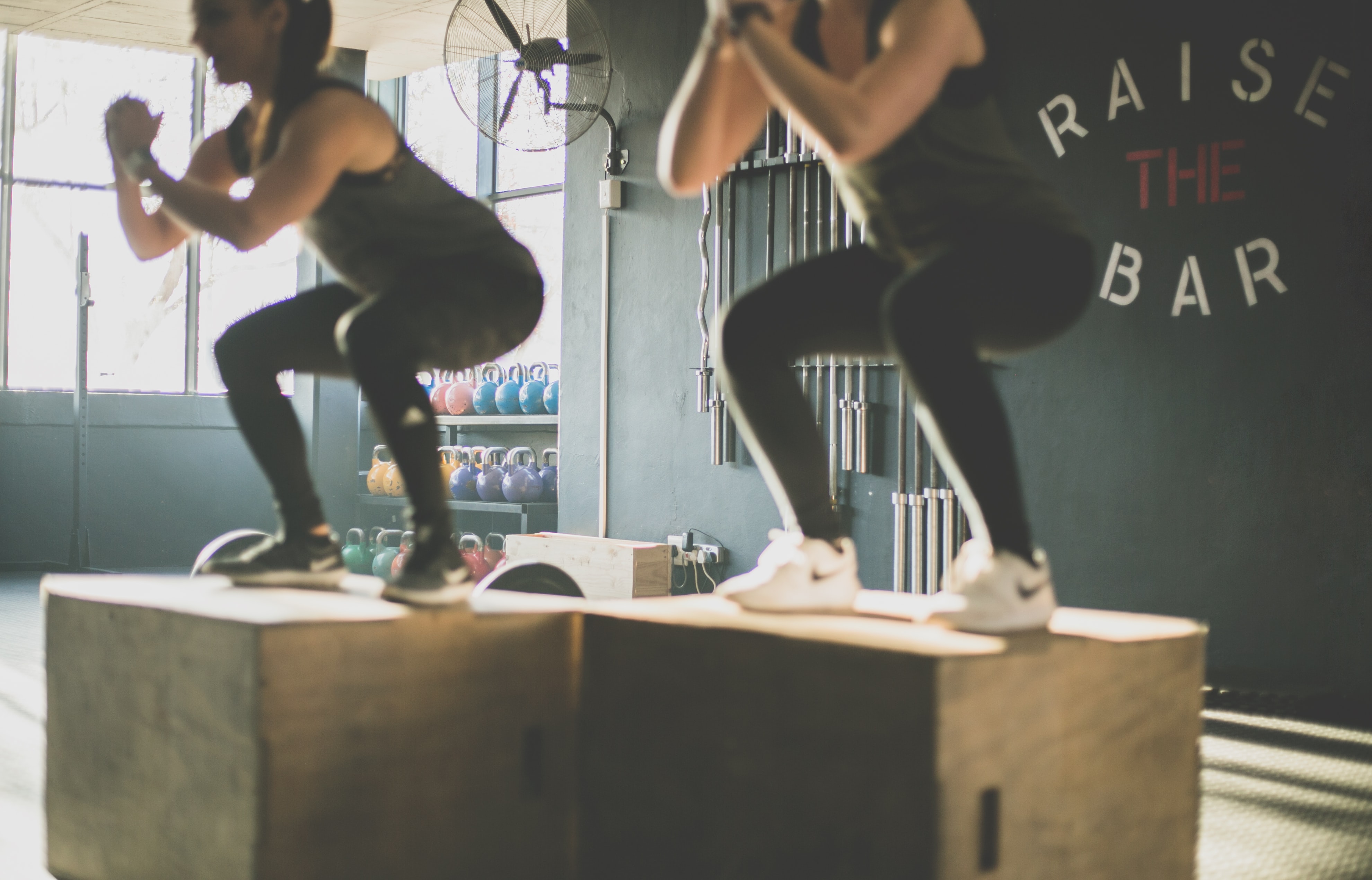 A functional fitness session; two women are jumping onto boxes.