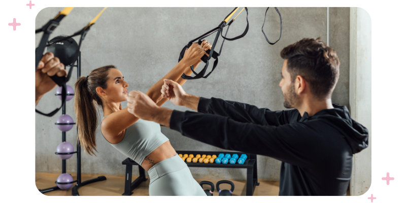 A coach conducting a client fitness assessment at the gym.