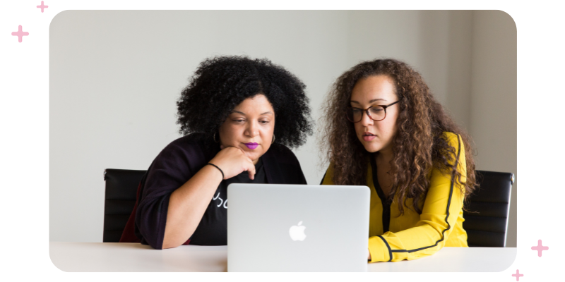 Two women working in front of a computer.