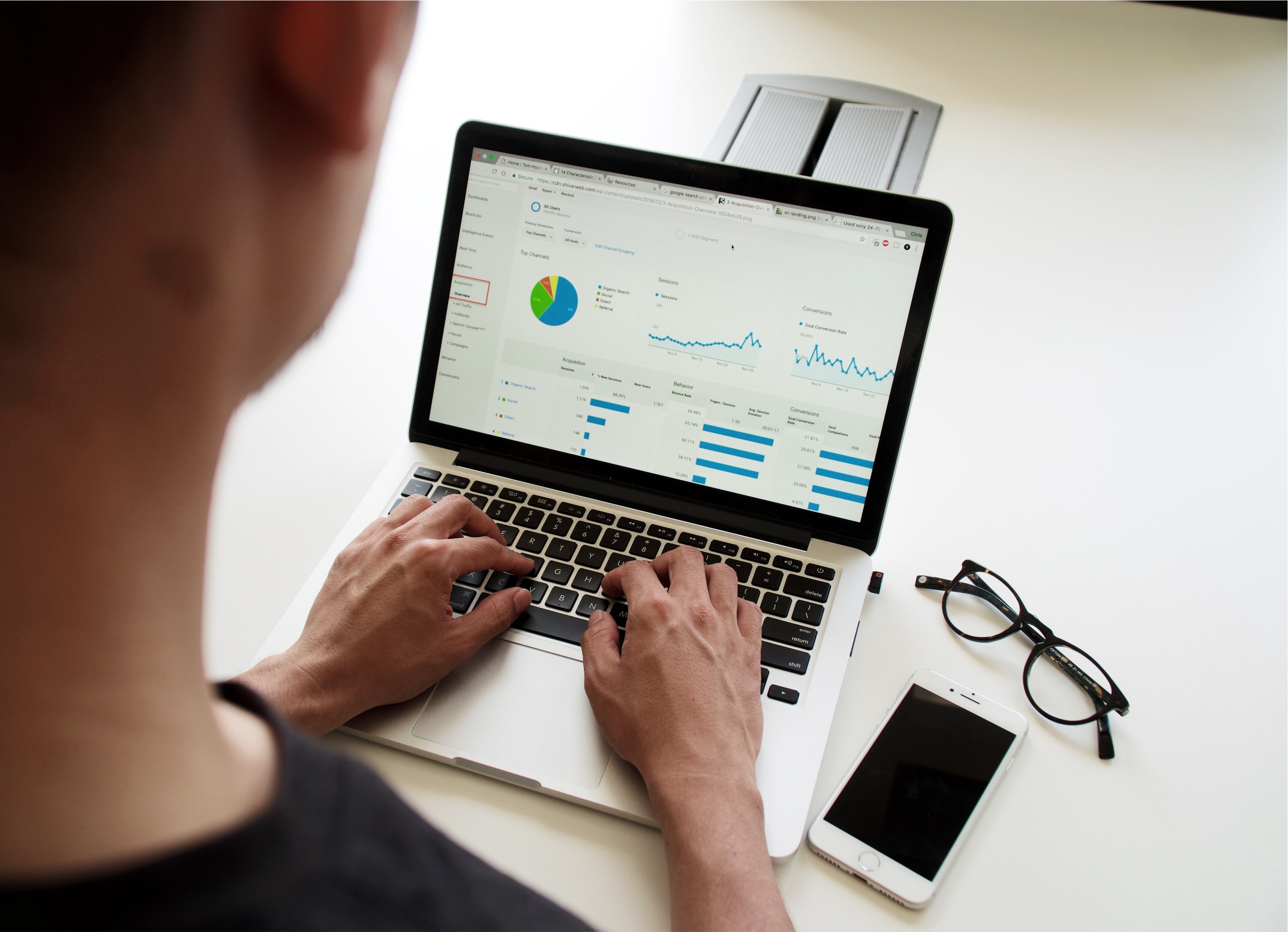 A man working on his laptop, looking at Google Analytics.