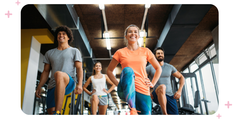 Group fitness class in a gym, everybody is smiling.