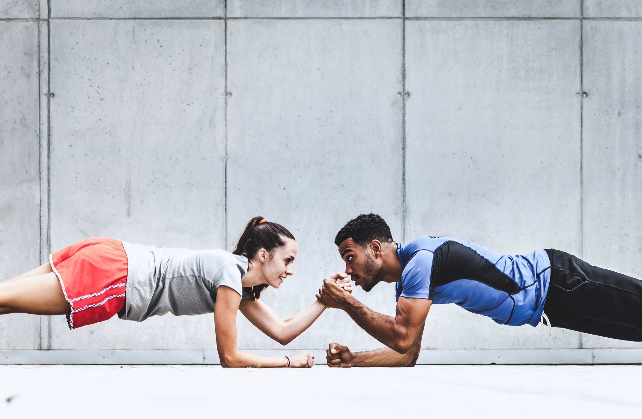 A fitness instructor high fives a fitness client while doing a plank